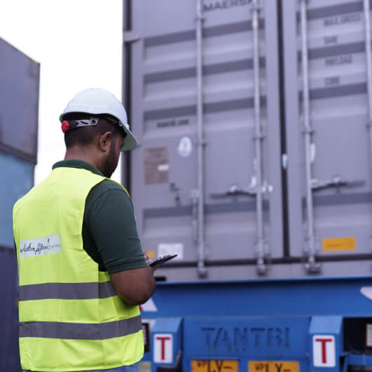 A worker performing a container survey, with a clipboard in hand