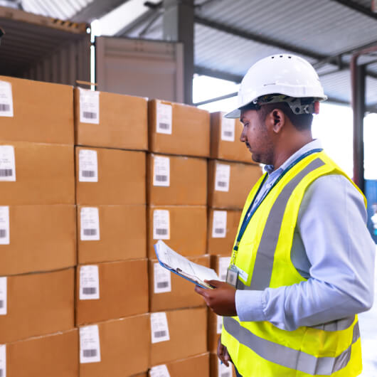 A worker performing a warehouse survey, with a clipboard in hand