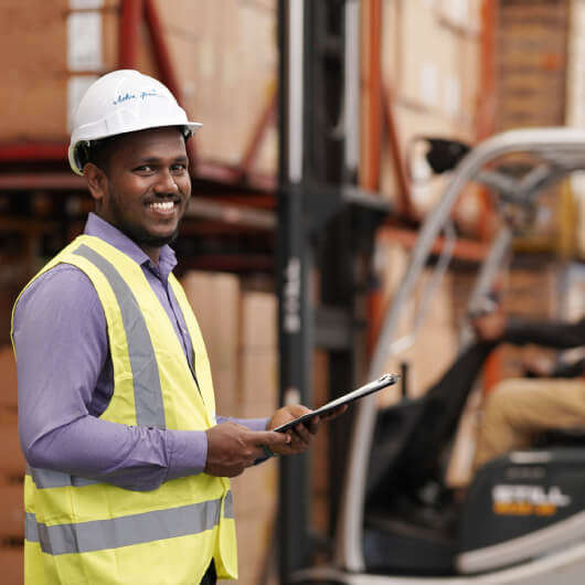 A worker performing a warehouse survey, with a clipboard in hand